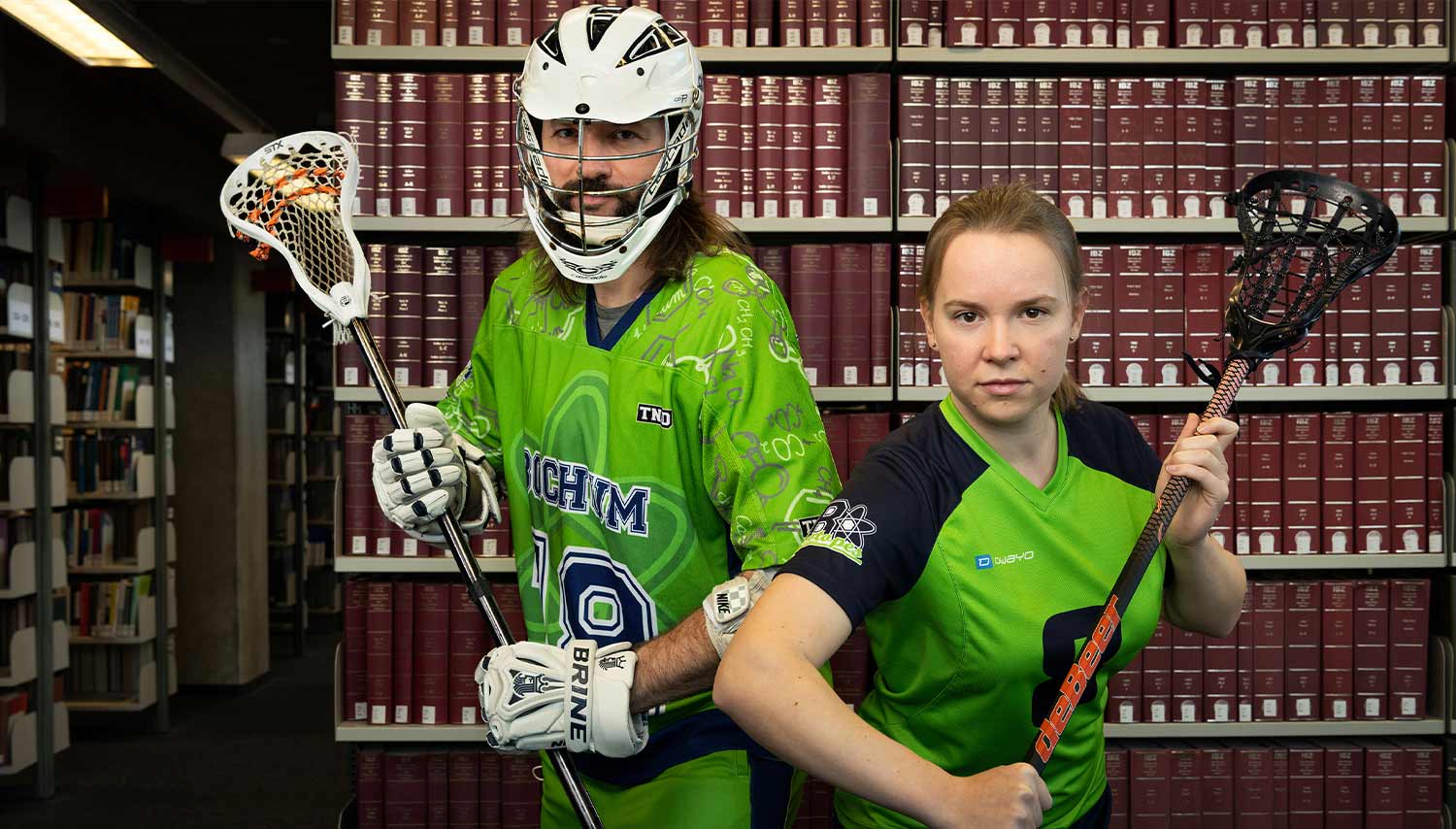 A male lacrosse player and a female lacrosse player in the library, © Heike Schmidt & Os Özkan